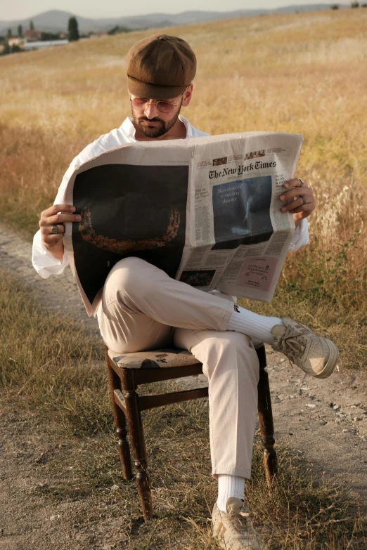 the man is sitting down while reading the paper