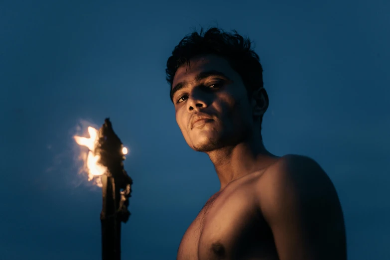 a shirtless man holding a fire lite