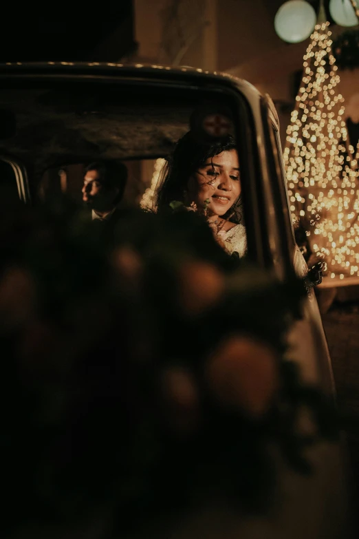 a woman looking out the window of a car at a lighted tree