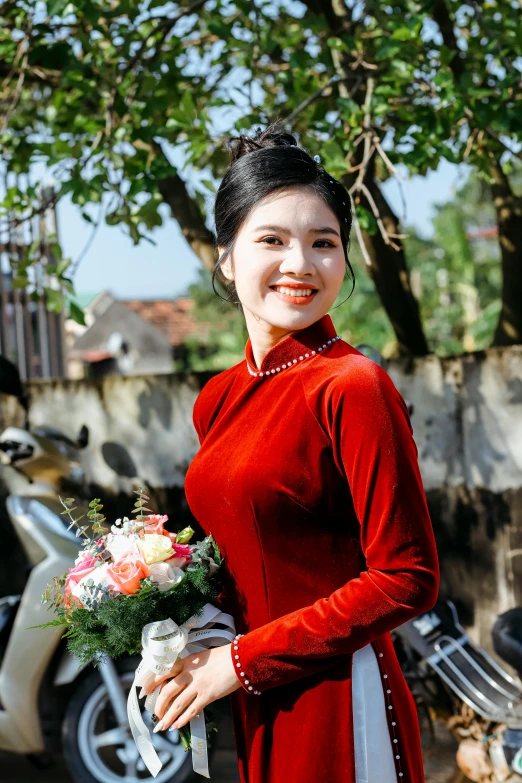 an oriental woman stands holding a bouquet and smiling