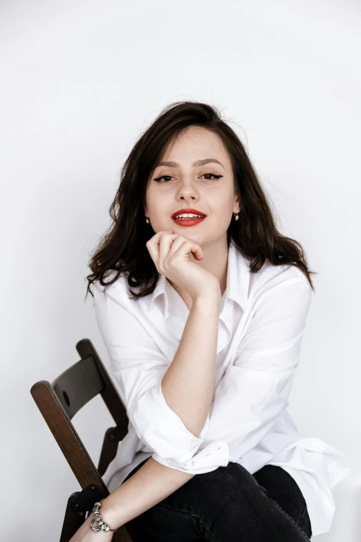 a woman sitting on a chair in a white shirt