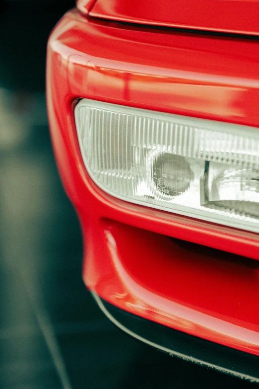 the headlight of a red car that is parked