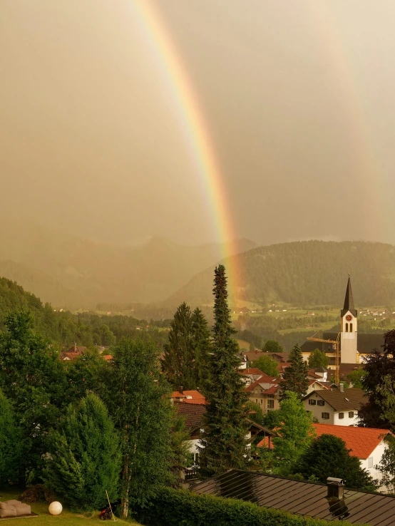 two rainbows over a small town in the mountains