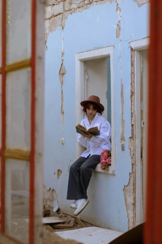 the woman sitting on a window sill reads a book