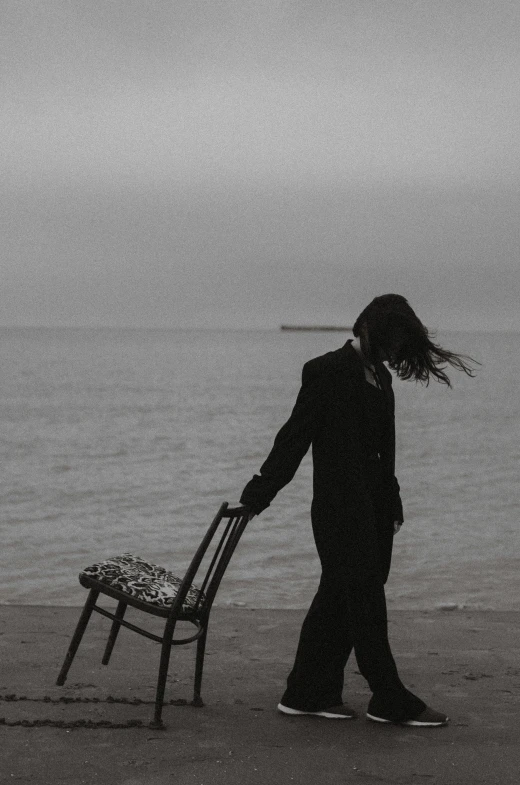 a man standing next to a chair on a beach