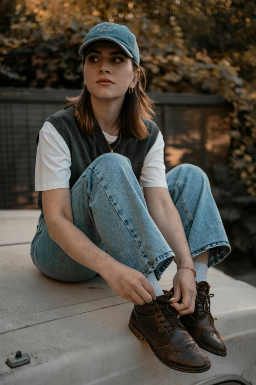 a  sitting on the ledge holding onto her shoes