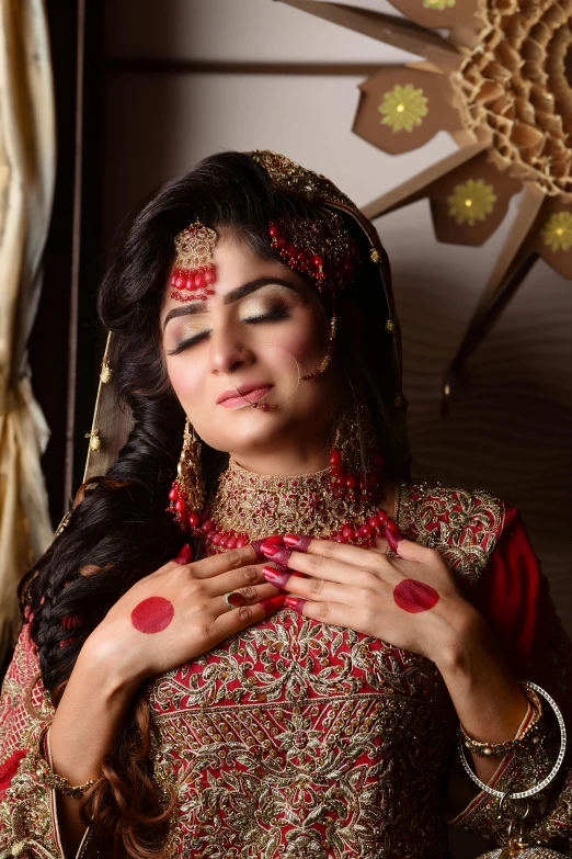 a woman wearing a red and gold dress standing with her eyes closed