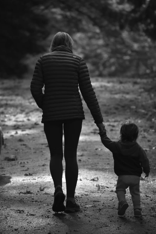 a woman and a small child are walking along a muddy path