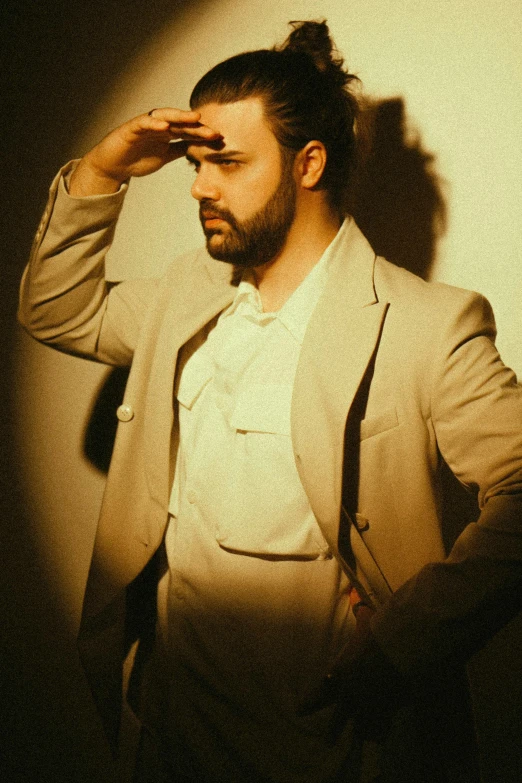 a person in a white suit and tie and holding his hand up