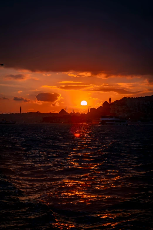 the sun is rising over the sea off a harbor