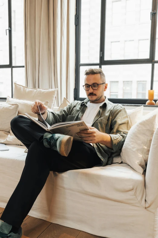 a man sits on a couch reading the newspaper