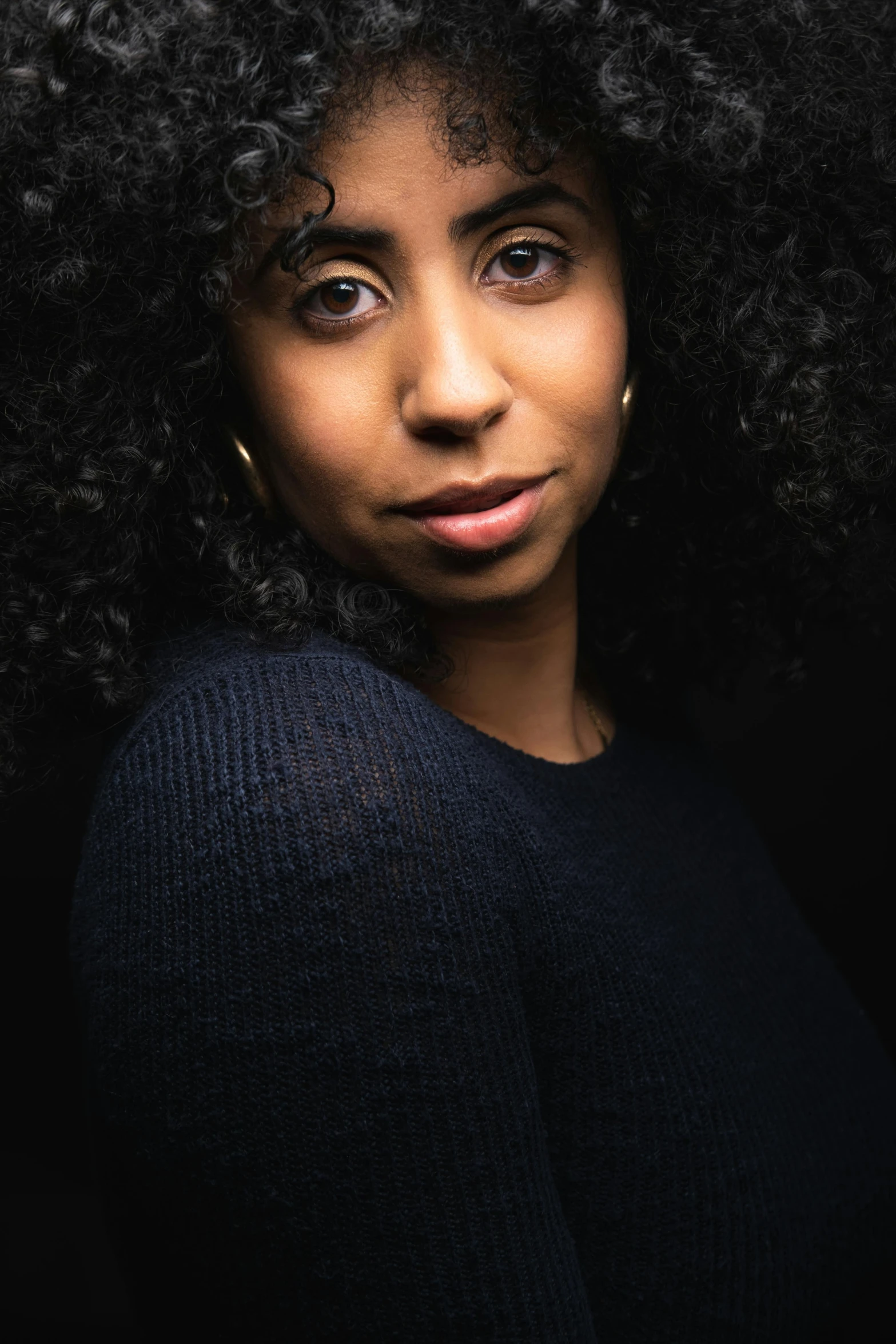 a woman with curly hair looks on in the background