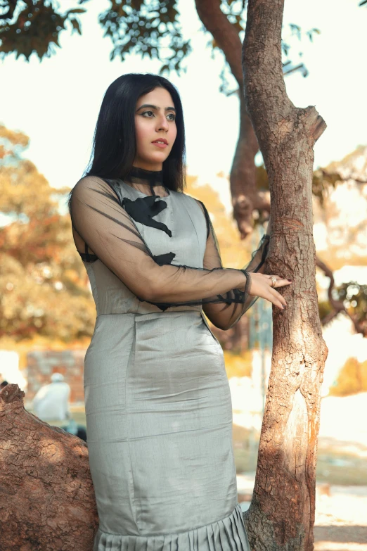 a woman standing next to a tree in a park