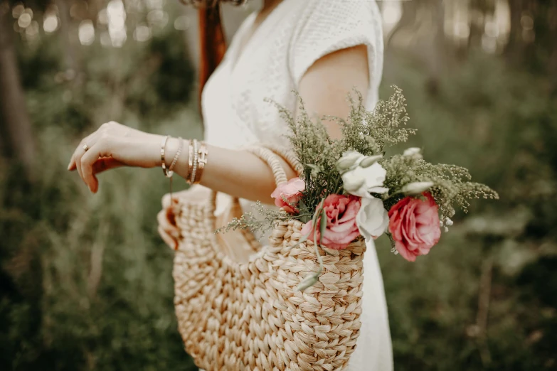 a woman holding an object in her hand and flowers in her bag