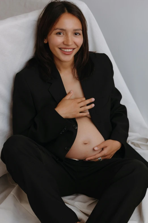 a pregnant woman with long hair sitting on the floor