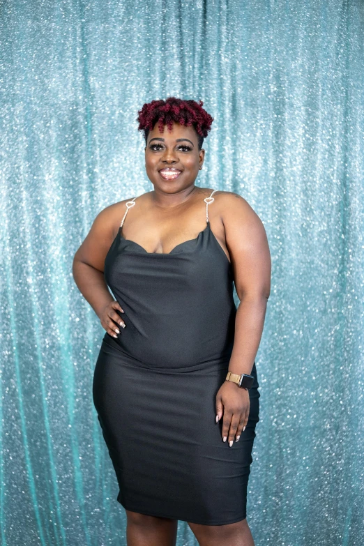 a woman in a grey dress standing next to a backdrop