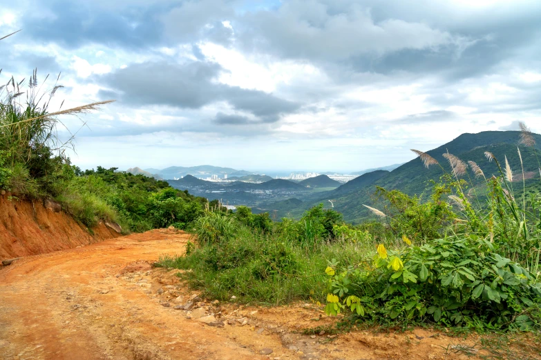 the dirt road is near the mountains as clouds cover them