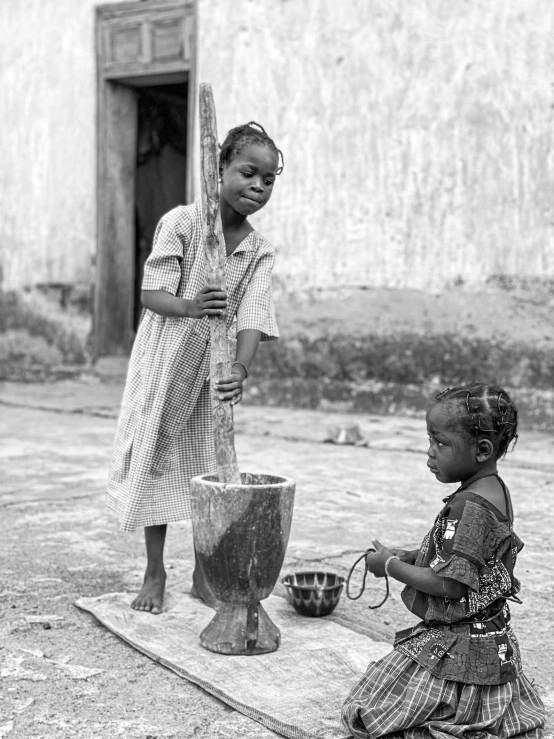 two children play with a big vase on the street