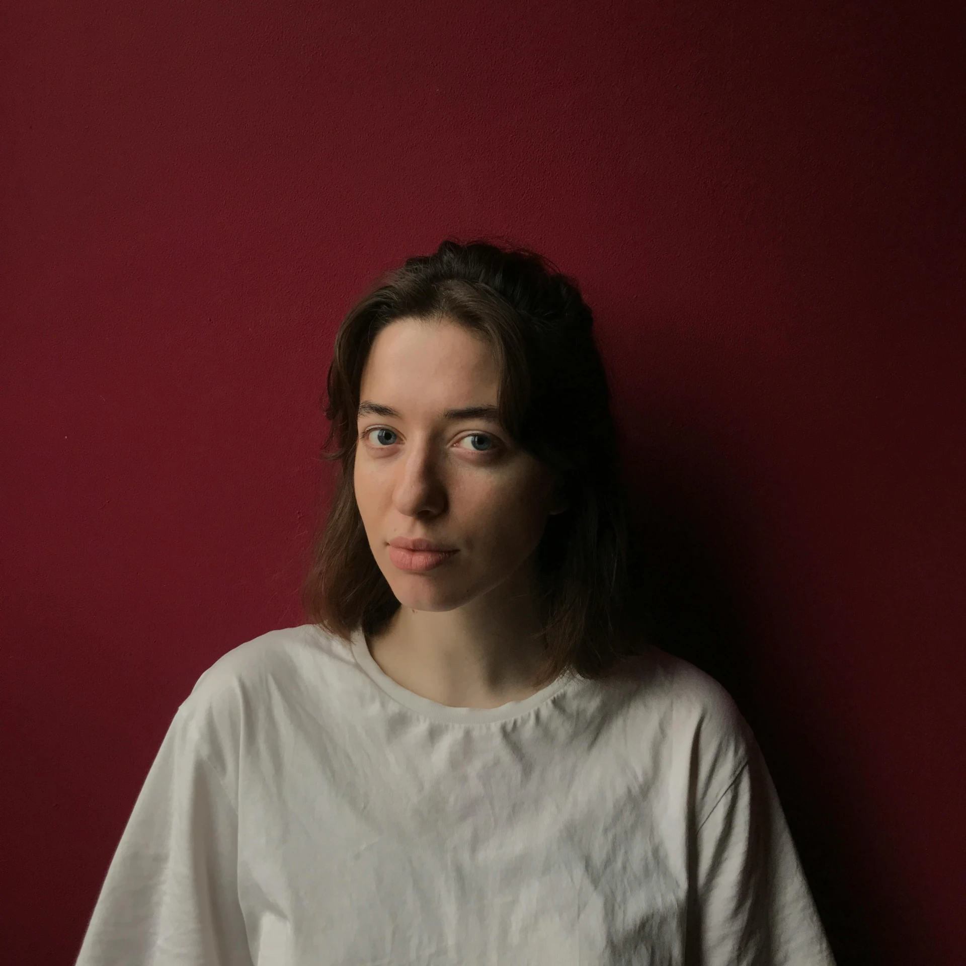 a woman poses for a picture against a red wall