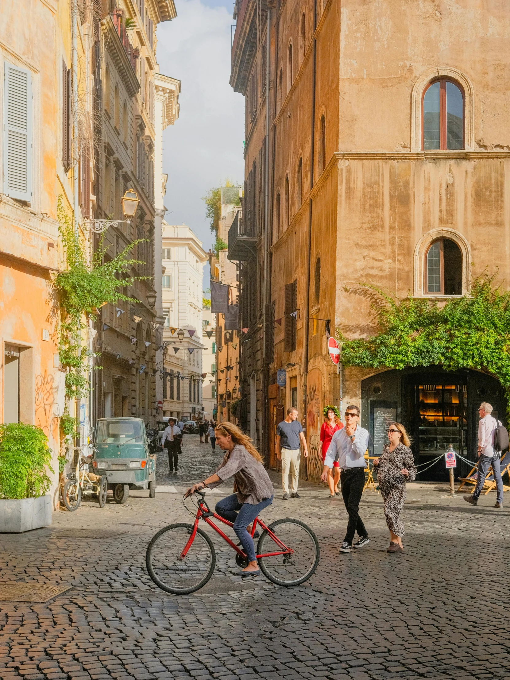 a woman riding on a bicycle down an old stone street