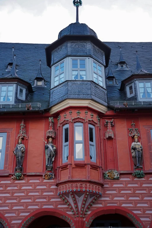 this large red building has many windows and statues on the front of it