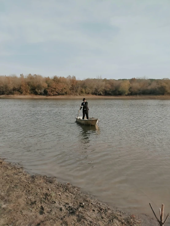 a man is standing on his canoe on the edge of a lake