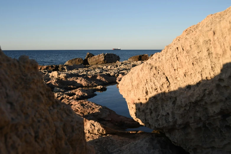 a large rock wall is next to the ocean