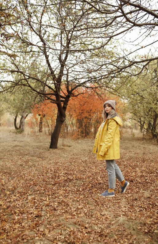 a child in the middle of a field wearing a yellow coat