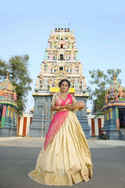 an indian woman in traditional attire in front of a tall temple