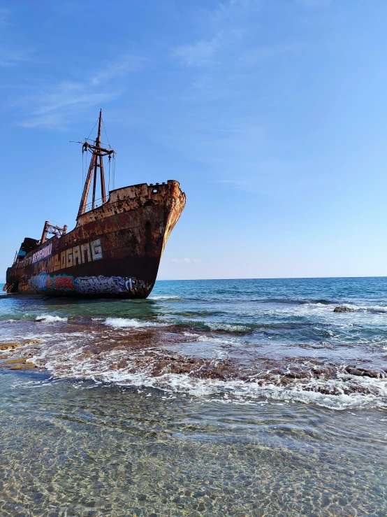 old ship sits on land in the water on a beach