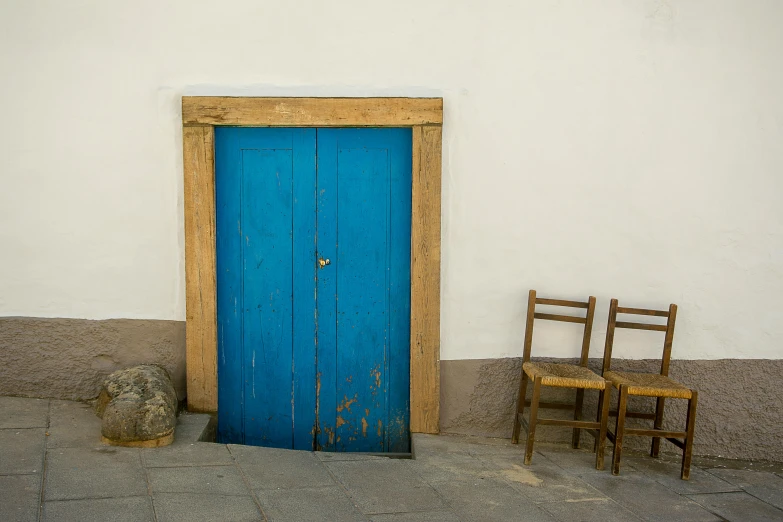 two chairs next to each other near a blue door