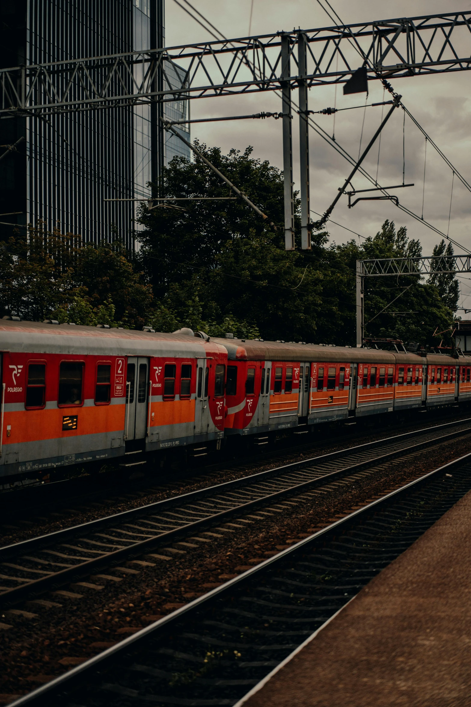 a train traveling past tall buildings under power lines