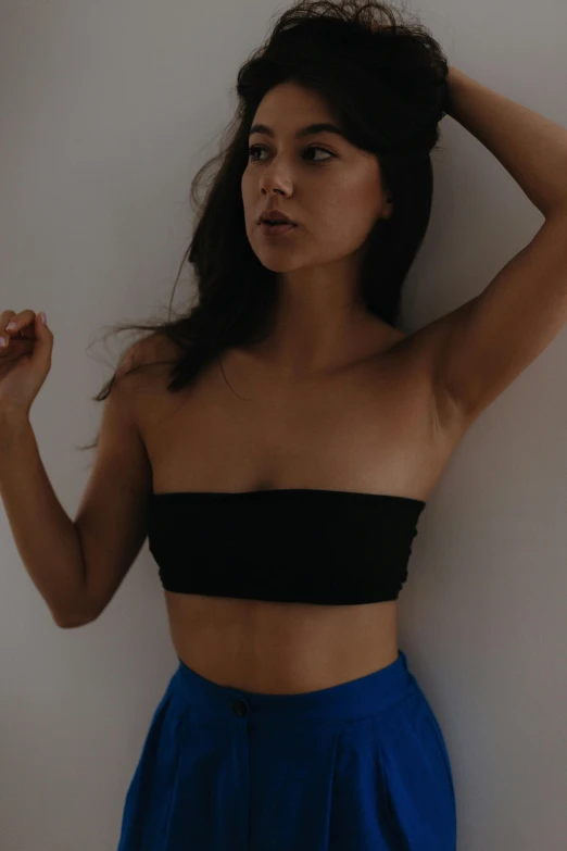 a woman in a black crop top and blue skirt