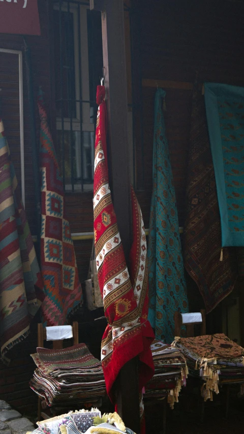 a woman with her foot on her arms looking up at some colorful rugs