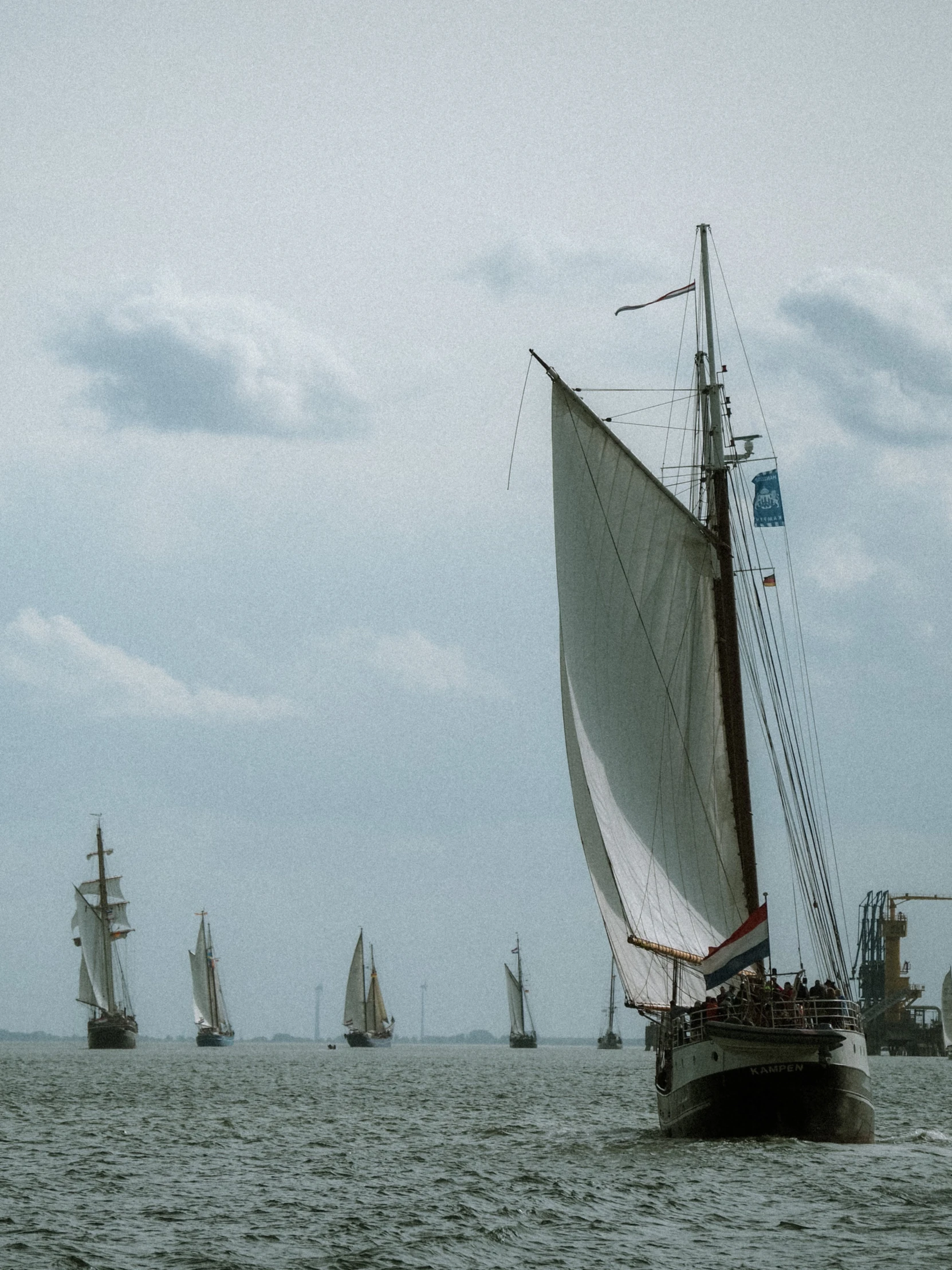 a group of boats sailing across a lake on a cloudy day