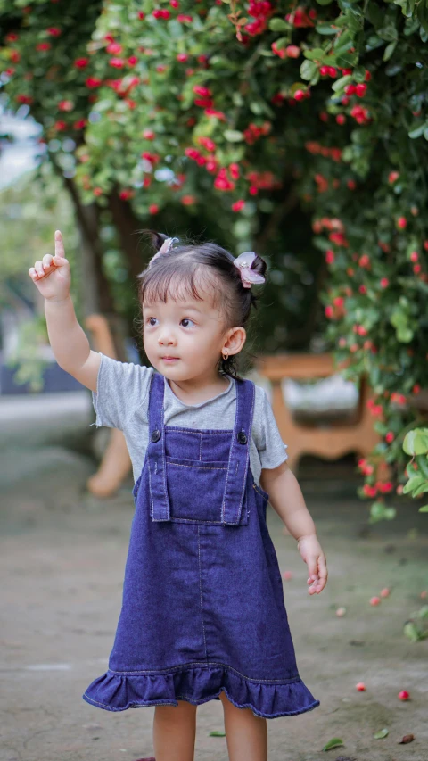 a young child standing on the ground with one hand in the air