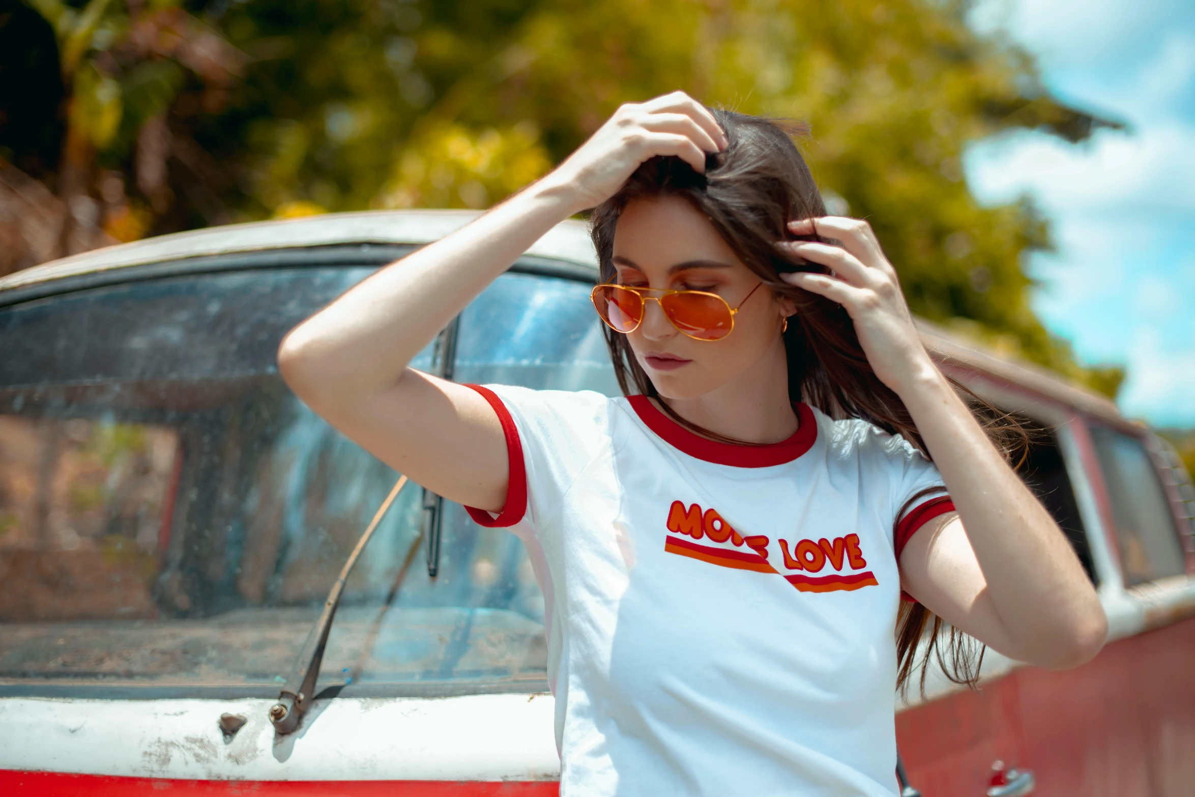 a woman adjusts sunglasses next to a car