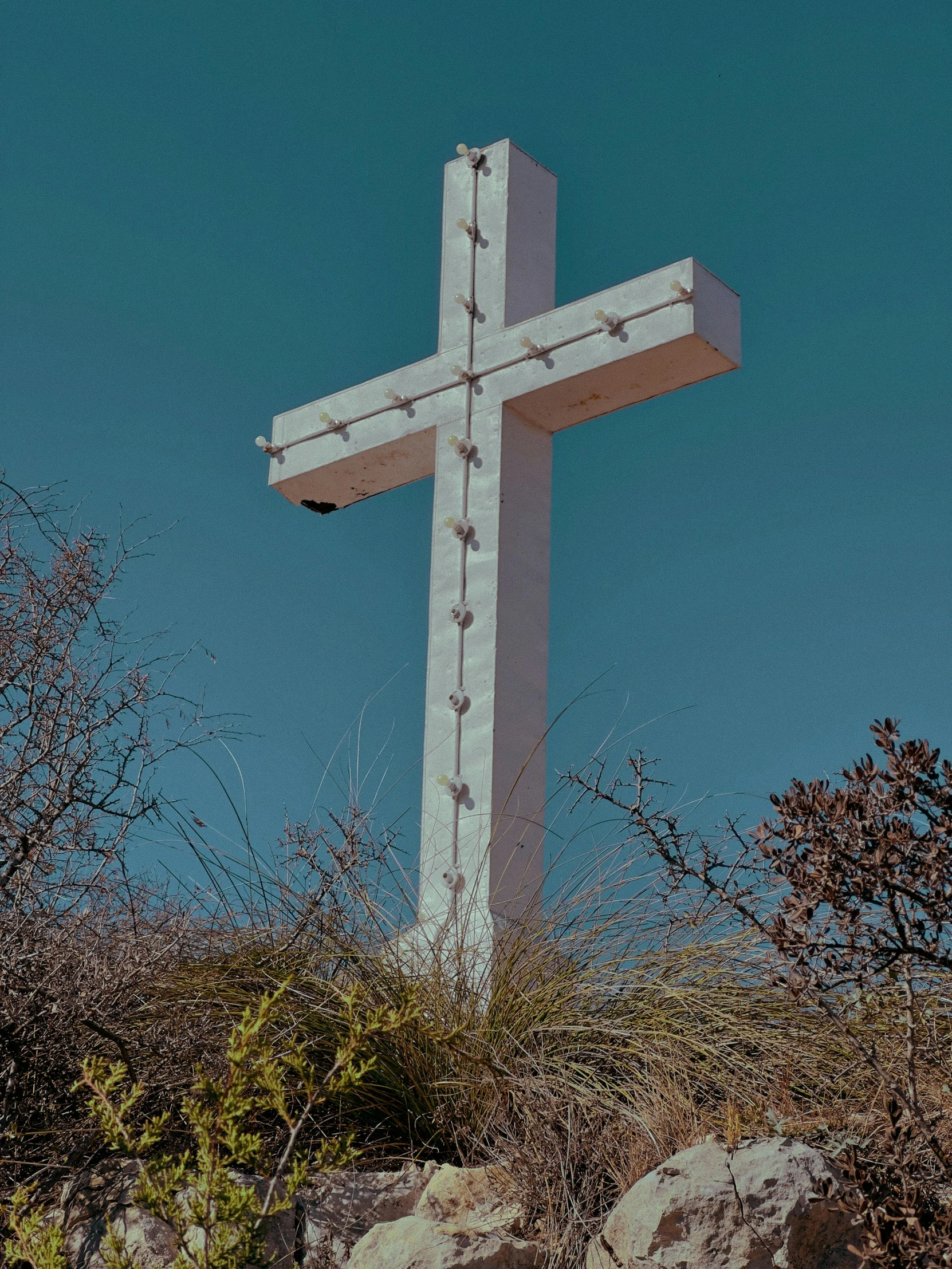 a large white cross surrounded by trees and rocks