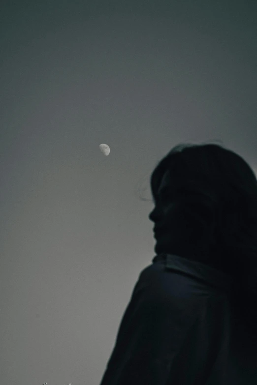 the back of a person's head with a moon in the distance