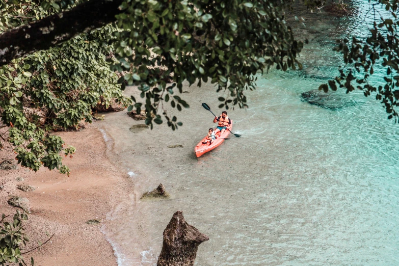 two people kayaking on the blue waters with trees