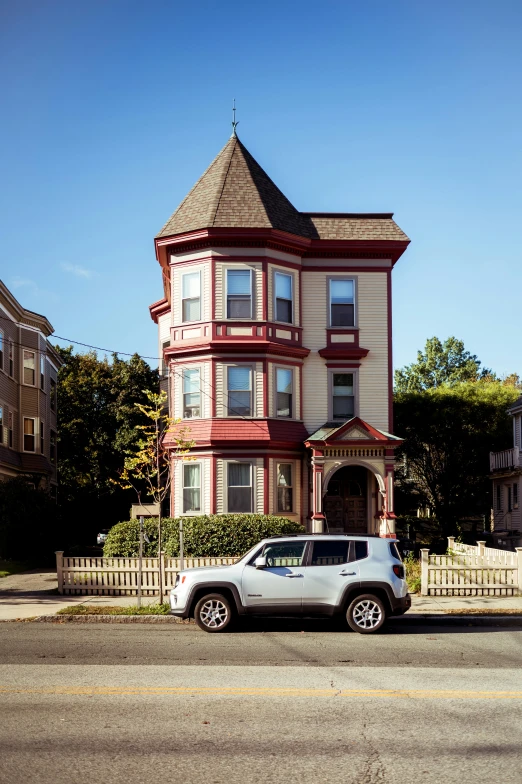 a gray car parked in front of a pink house