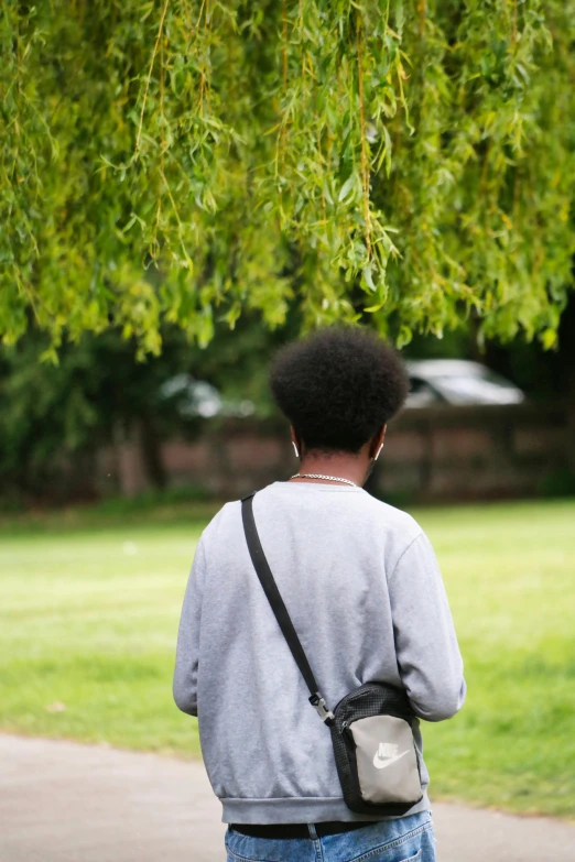 a woman walking down a pathway under a tree