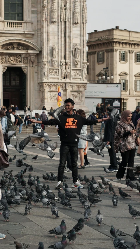 people standing outside surrounded by many birds
