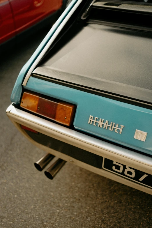 a turquoise hatchback parked next to a red car