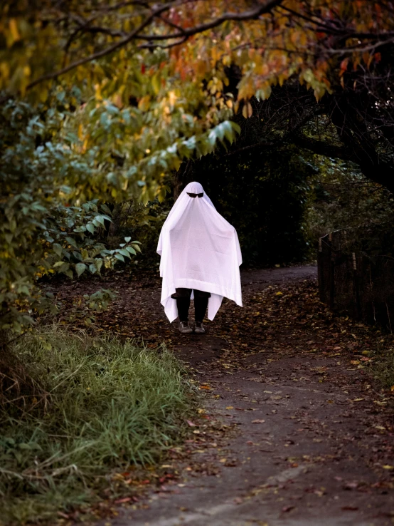 a woman walking down a trail holding a white umbrella