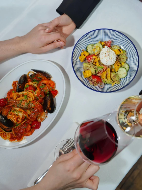 a table with a plate of pasta and wine