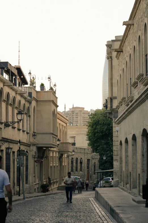 three people are walking down an old city street