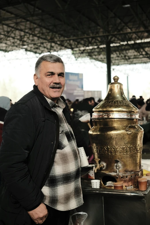 an older gentleman standing next to a large golden urn