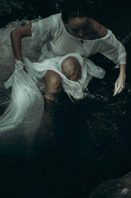 woman sitting in a pool in the dark with an umbrella on