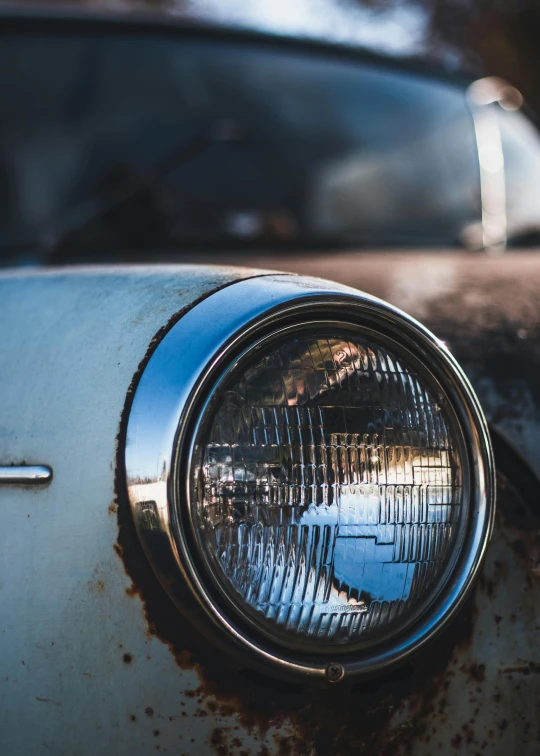 an old rusted out car light reflecting in the mirror